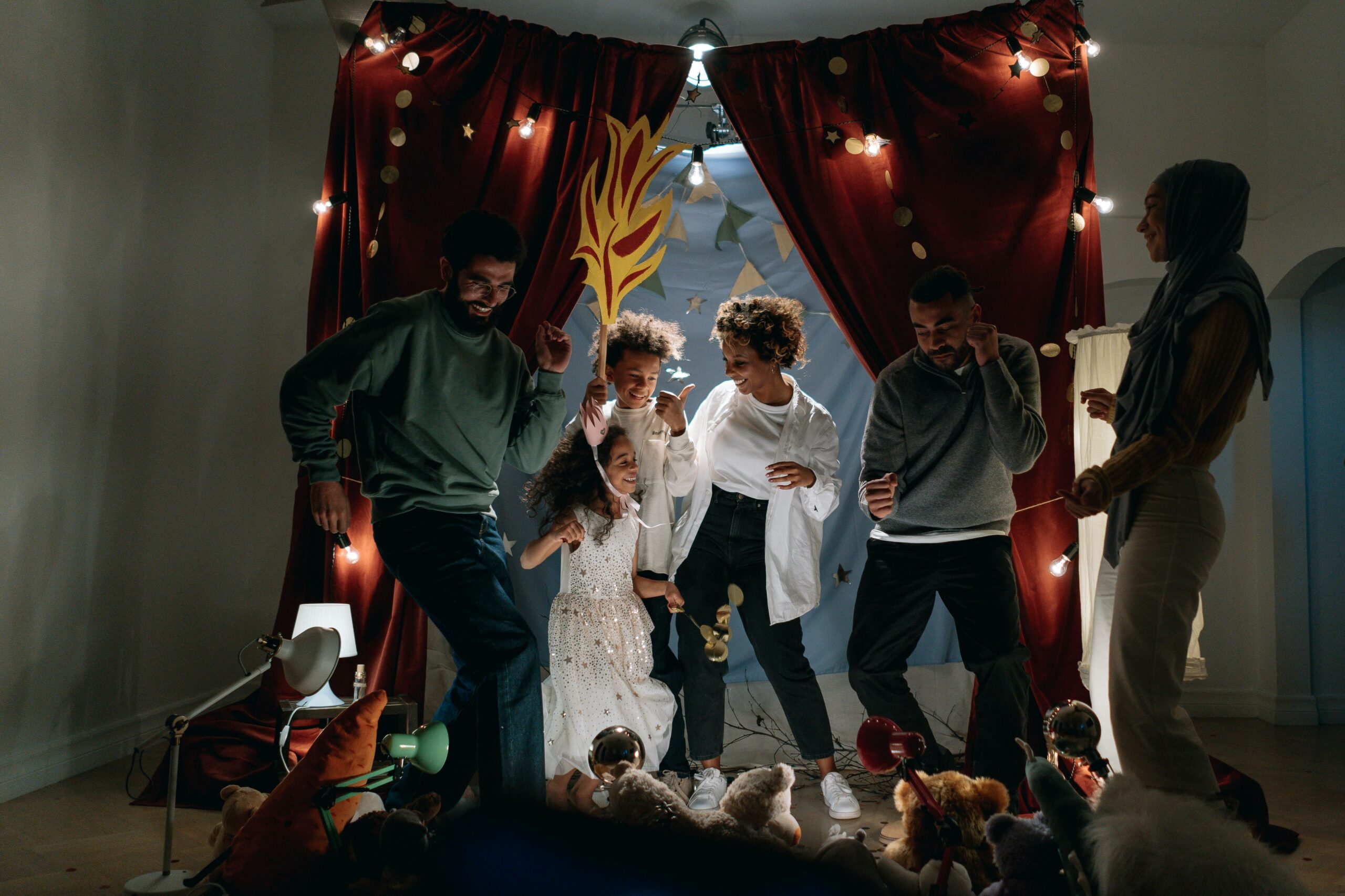 A joyful family bonding session with children performing indoors under fairy lights.