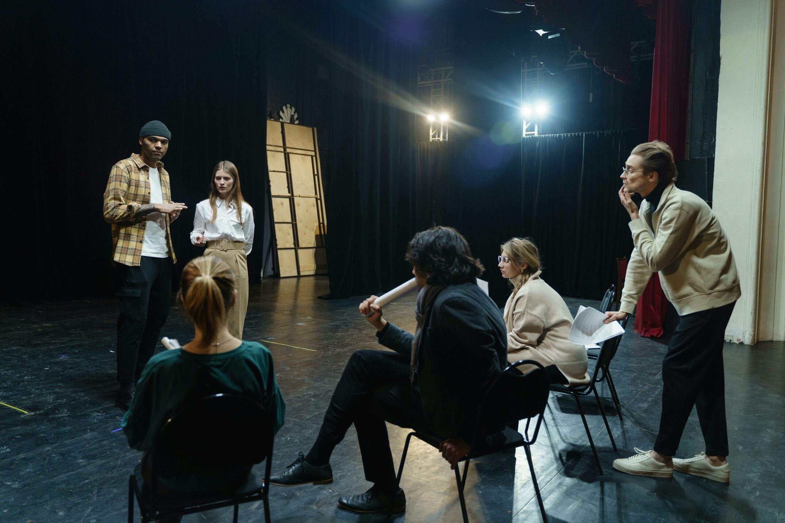 Actors rehearsing on stage with director's guidance in a theater for a live performance.